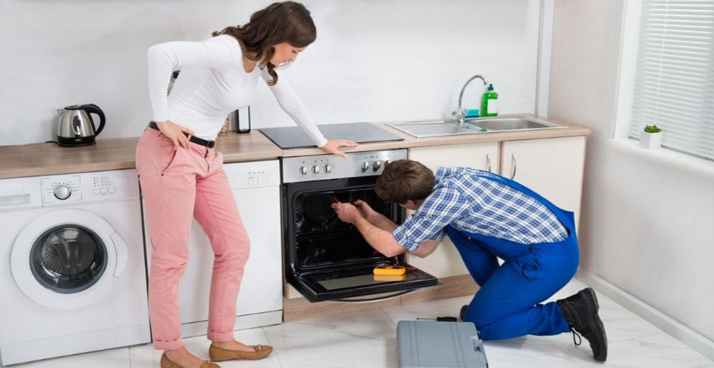 Technicien spécialisé effectuant une intervention de maintenance sur électroménager dans une cuisine domestique française